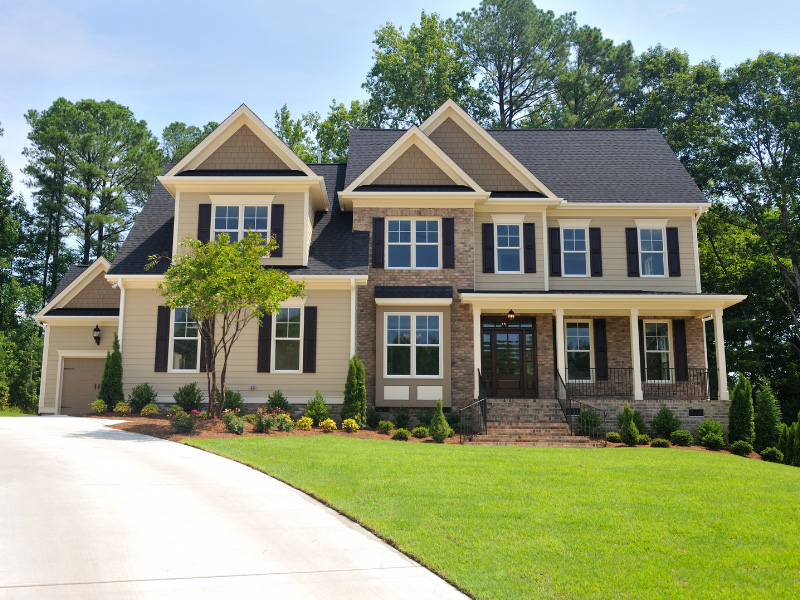 two-story-home-with-beige-siding-vibrant-green-lawn-and-long-driveway