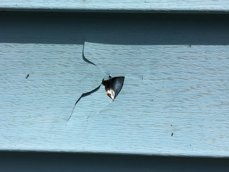 siding-damage-showing-hole-in-blue-vinyl-siding-panel