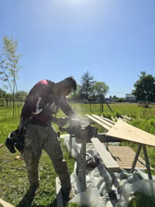 Sister-siding-crew-member-sawing-wood-for-siding-repair