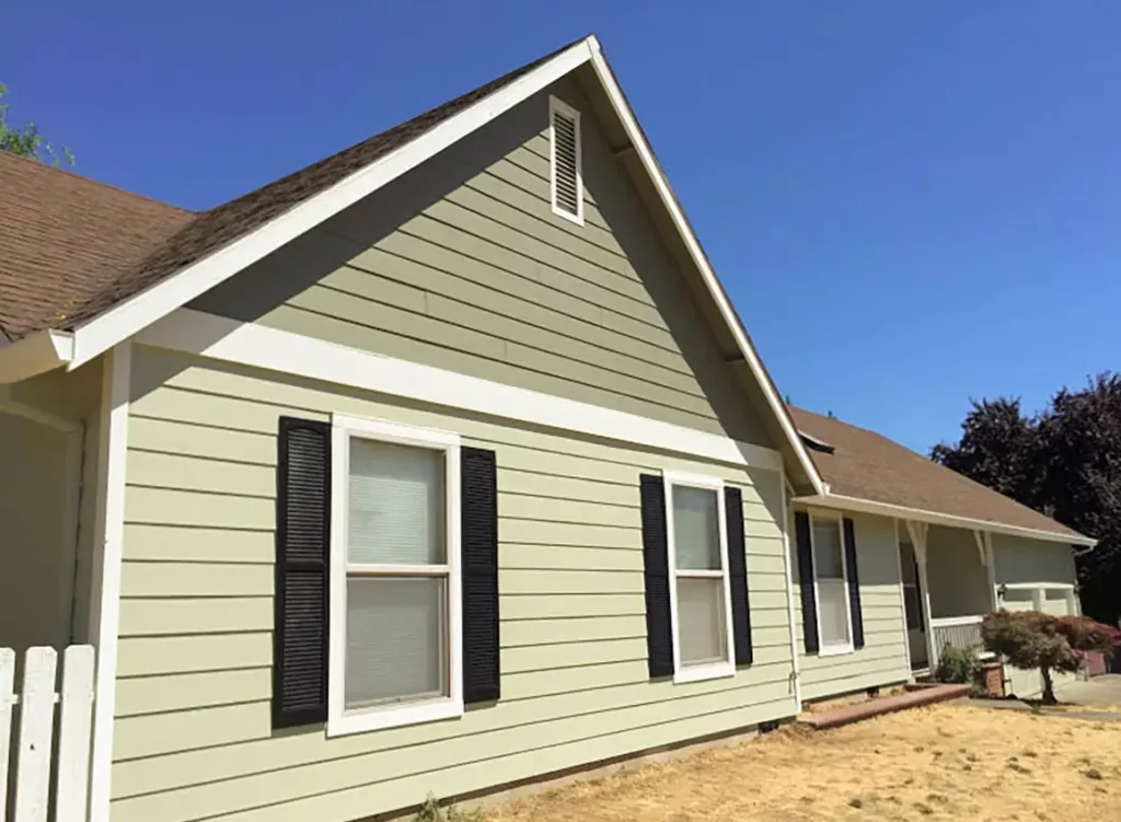 after of siding project now painted green and light green refinished siding with brown accent window coverings